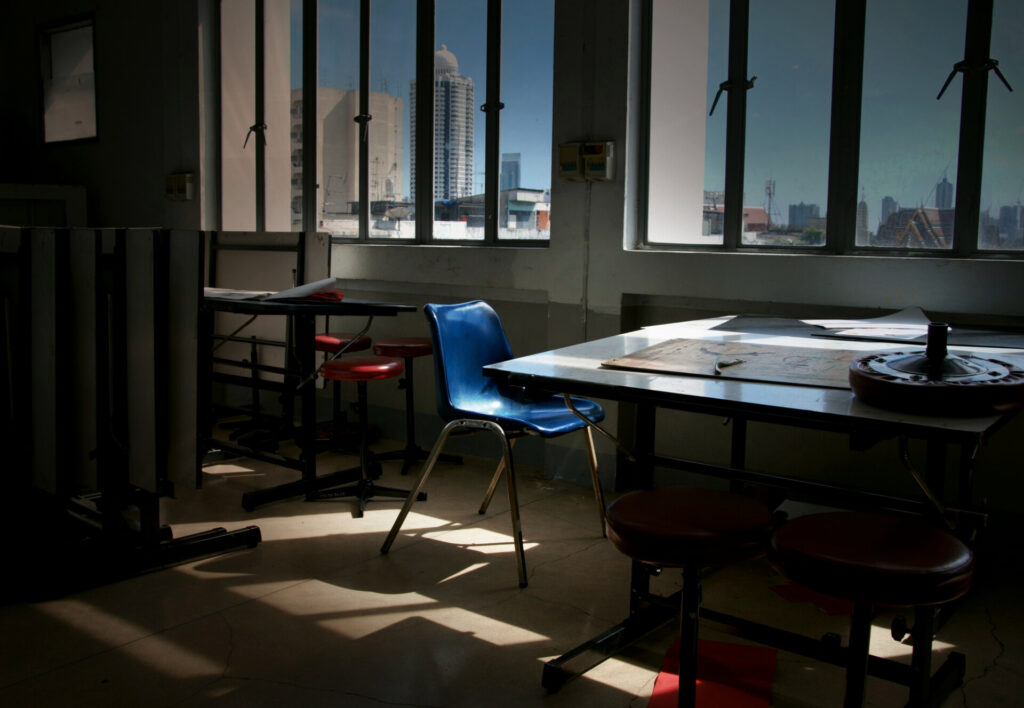 ADR and mediation: resolving employment disputes faster - Wolf Law Wolf Law 14437 Dim workshop/classroom with a blue chair at a table by large windows overlooking a city skyline.