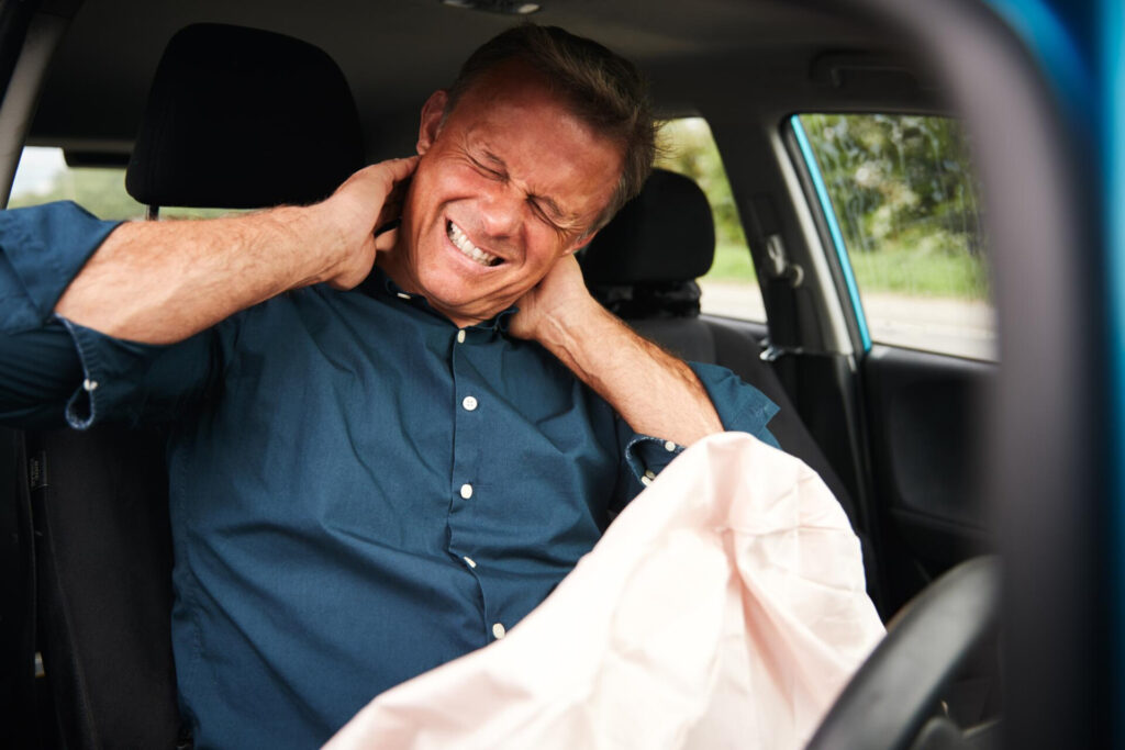 Wolf Law are the number one accident solicitors in Liverpool and the Wirral, supporting claims for personal injury claims in Liverpool Wolf Law are the number one accident solicitors in Liverpool and the Wirral, supporting claims for personal injury claims in Liverpool Man in a blue shirt sits in a car, gripping his neck with a pained expression as if in neck pain.