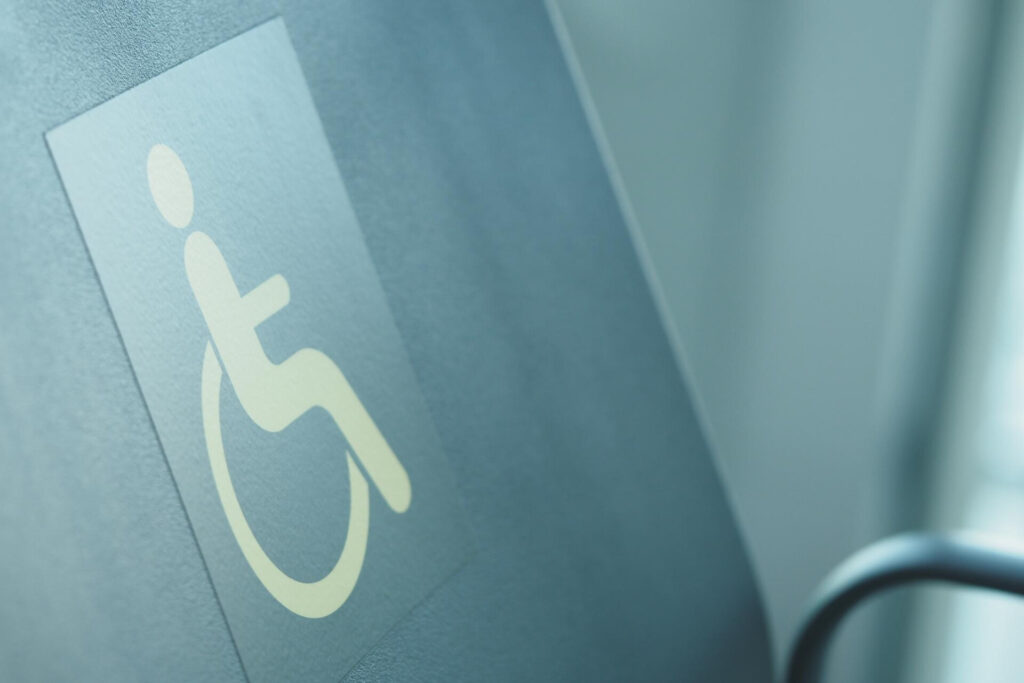 Disability Support at Work: Your Employment Rights and Legal Remedies - Wolf Law Wolf Law 35250 Wheelchair accessibility sign close-up on a blue wall surface, showing the white icon partially.