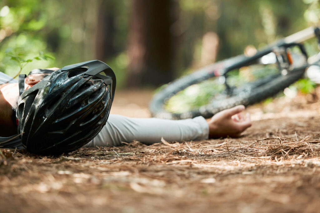 Rehabilitation support key in Solicitors’ claim for cyclist left partially blinded - Wolf Law Wolf Law 222842 Cyclist lying on a forest trail beside a fallen bike, wearing a helmet.