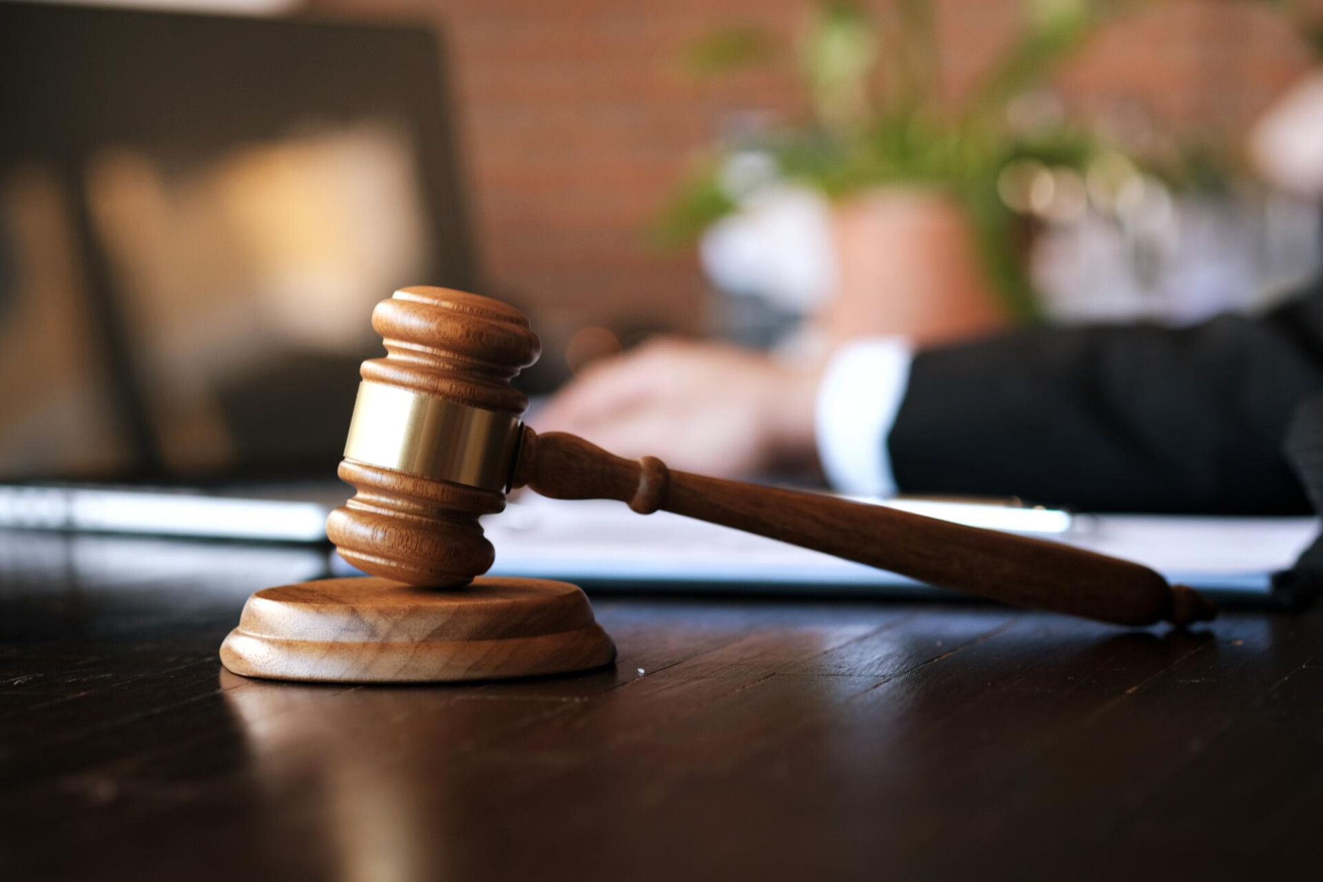Wooden judge's gavel resting on a desk in a courtroom setting, symbolizing justice or legal proceedings.