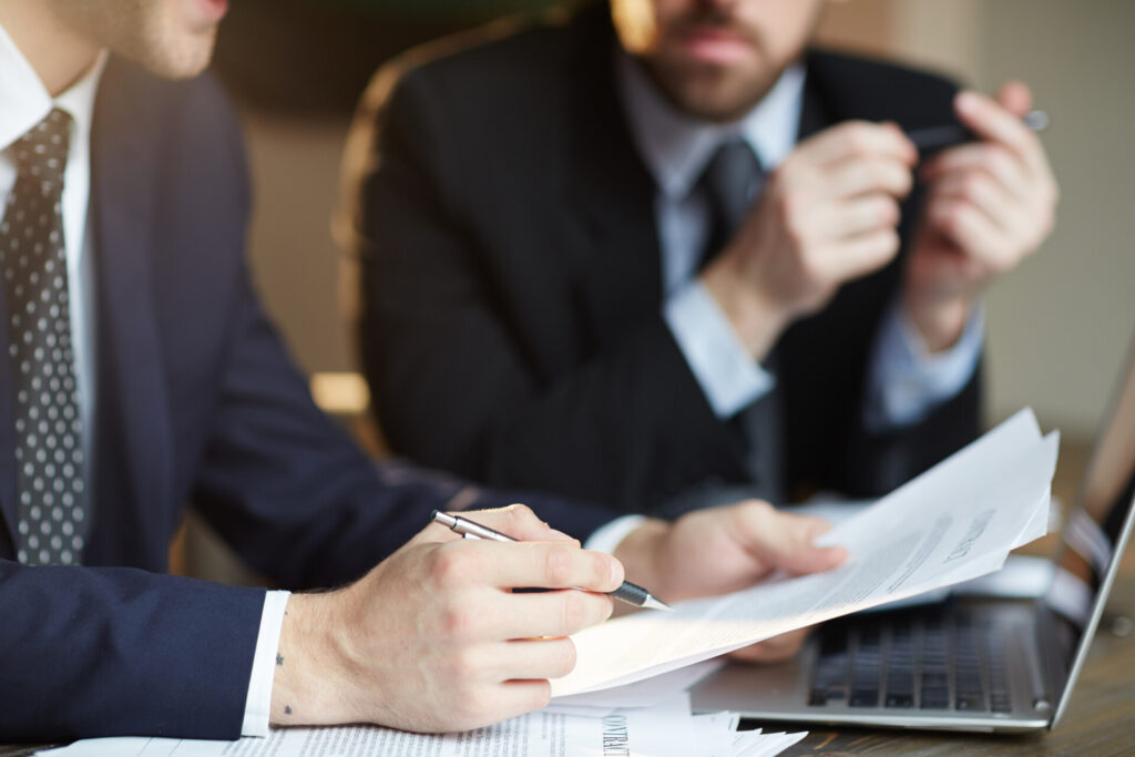 Wolf Law are the number one accident solicitors in Liverpool and the Wirral, supporting claims for personal injury claims in Liverpool Wolf Law are the number one accident solicitors in Liverpool and the Wirral, supporting claims for personal injury claims in Liverpool Two businessmen in suits review documents at a desk, one is writing with a pen while a laptop sits nearby.