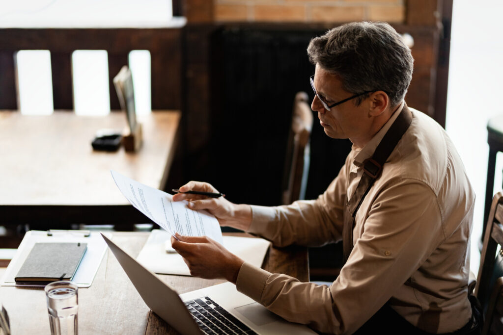 Wolf Law are the number one accident solicitors in Liverpool and the Wirral, supporting claims for personal injury claims in Liverpool Wolf Law are the number one accident solicitors in Liverpool and the Wirral, supporting claims for personal injury claims in Liverpool Man in a beige shirt and glasses reads a document at a wooden desk with a laptop nearby.
