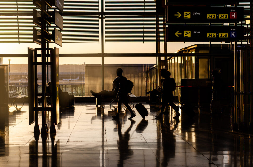 Wolf Law are the number one accident solicitors in Liverpool and the Wirral, supporting claims for personal injury claims in Liverpool Wolf Law are the number one accident solicitors in Liverpool and the Wirral, supporting claims for personal injury claims in Liverpool Silhouettes of travelers with rolling bags walking through an airport concourse at sunset, with overhead gate signs.